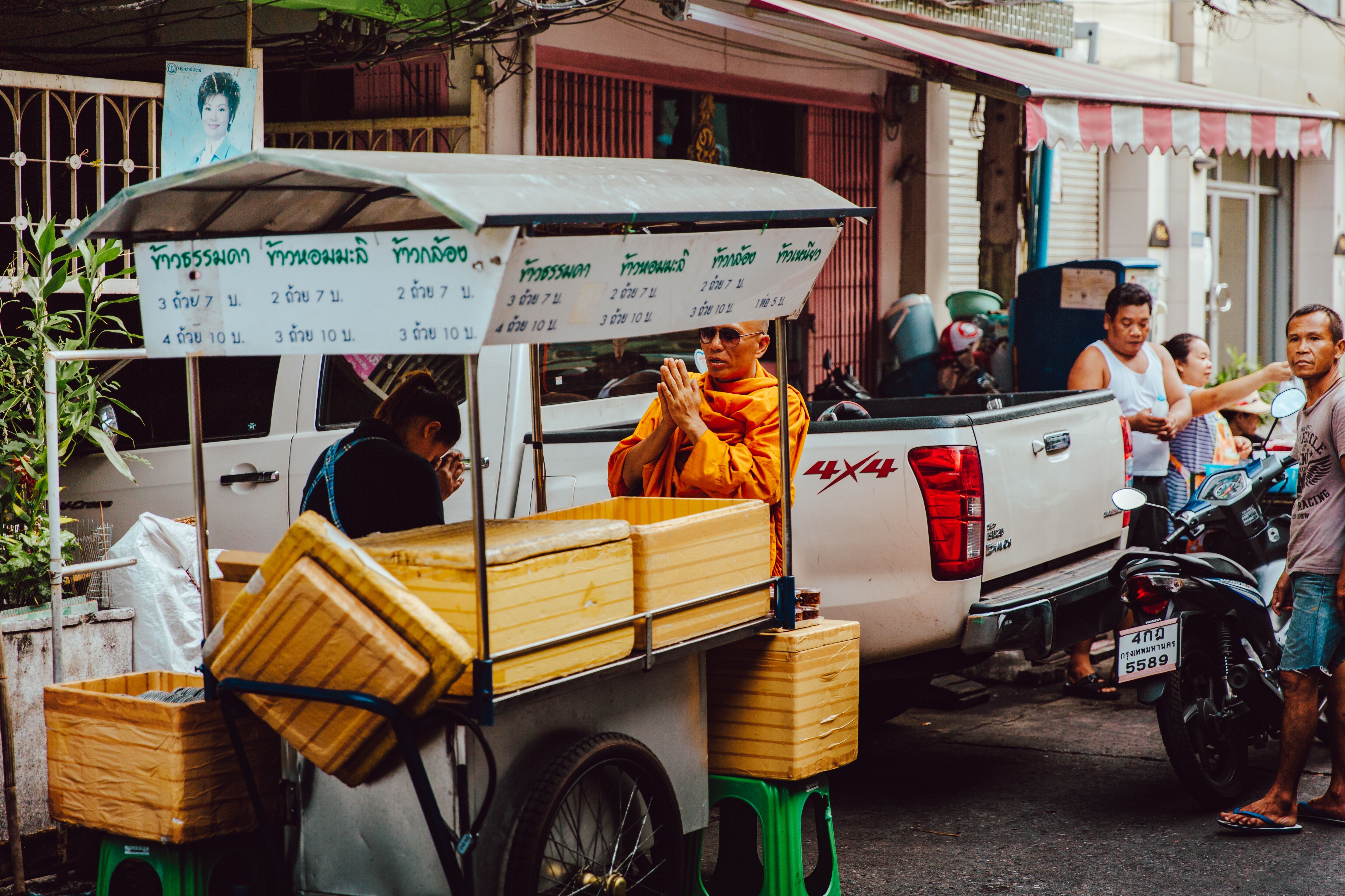 The Wai greeting taking place between a Buddhist monk and street food vendor in Thailand
