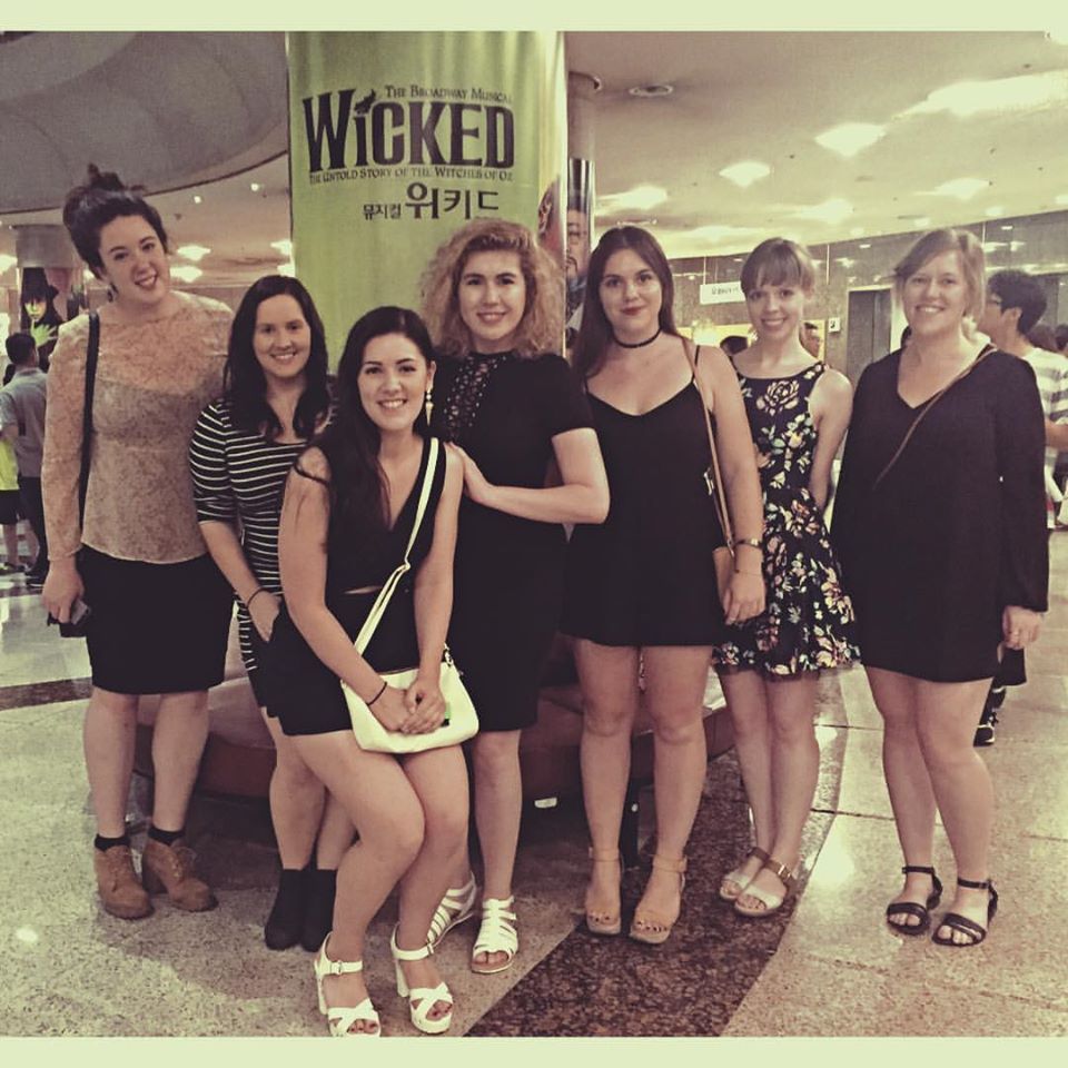 women gathered in front of theatre poster