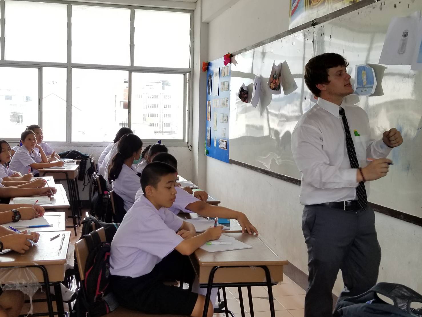 teacher writing on whiteboard in front of classroom