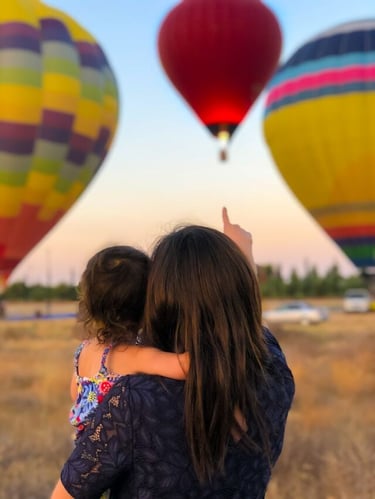 woman pointing at hot air baloons