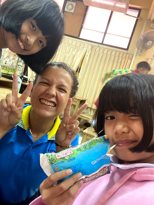 woman with two students smile at camera while woman makes peace signs