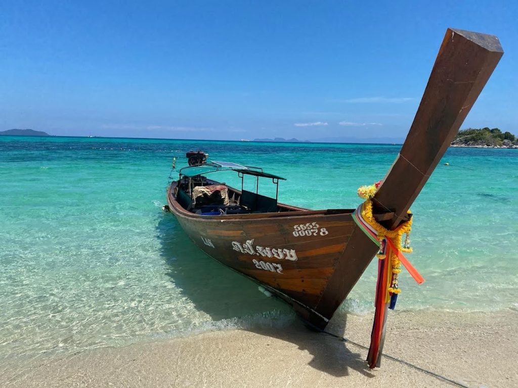 wodden boat is beached with blue water in background