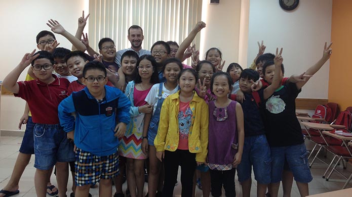 A teacher poses with his students in a Vietnamese classroom. 