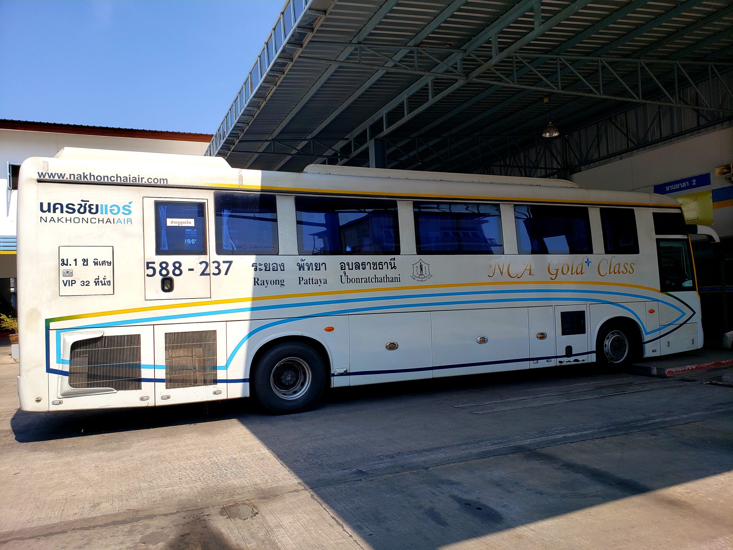 white bus with thai writing parked at station