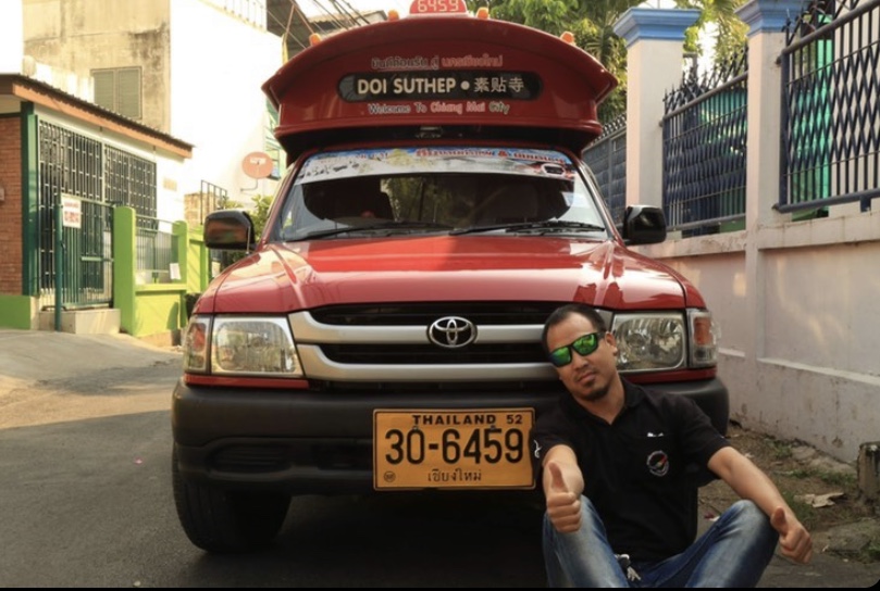 red songthaew truck with driver seated in front